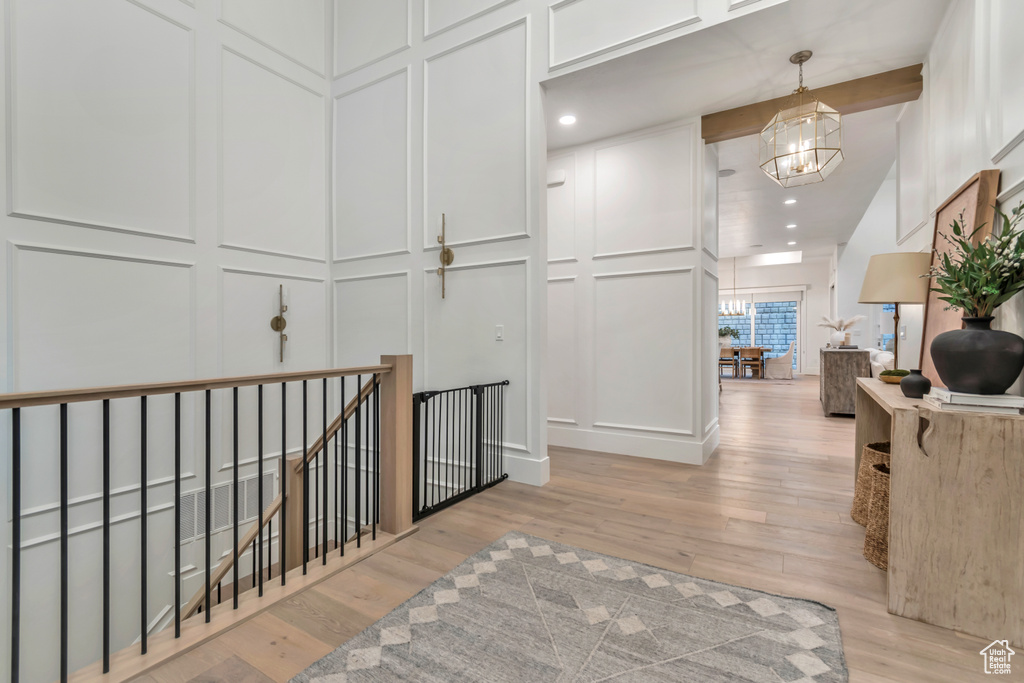 Corridor featuring a decorative wall, a chandelier, light wood-type flooring, an upstairs landing, and recessed lighting