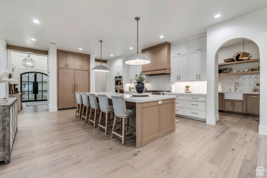 Kitchen with a sink, tasteful backsplash, recessed lighting, an island with sink, and light countertops