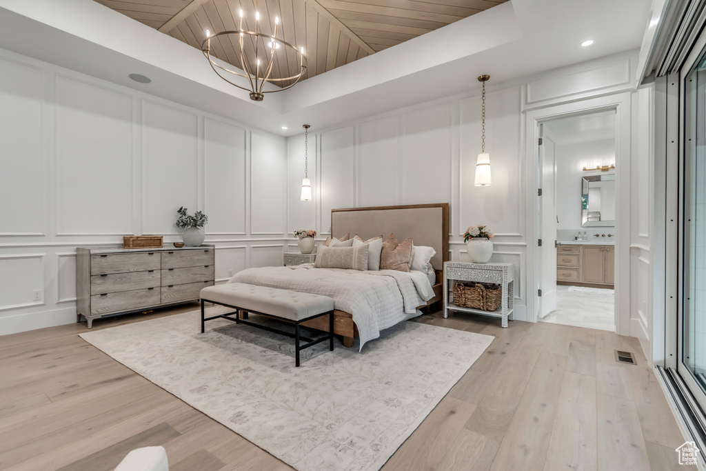 Bedroom with a decorative wall, light wood-style floors, a chandelier, recessed lighting, and connected bathroom