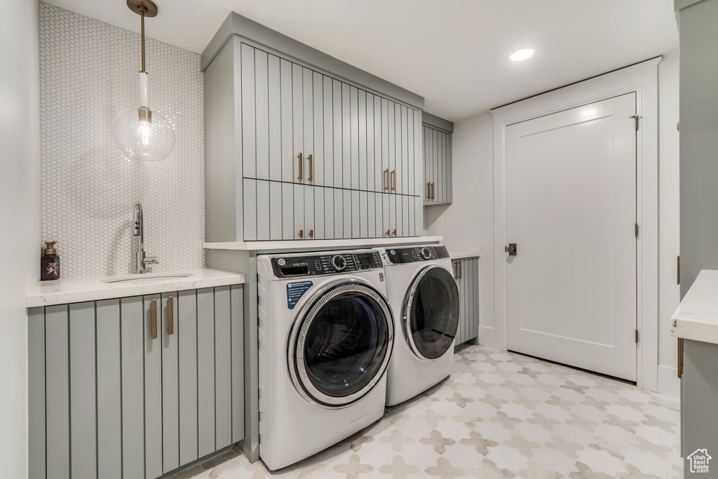 Laundry area featuring separate washer and dryer, cabinet space, and light floors