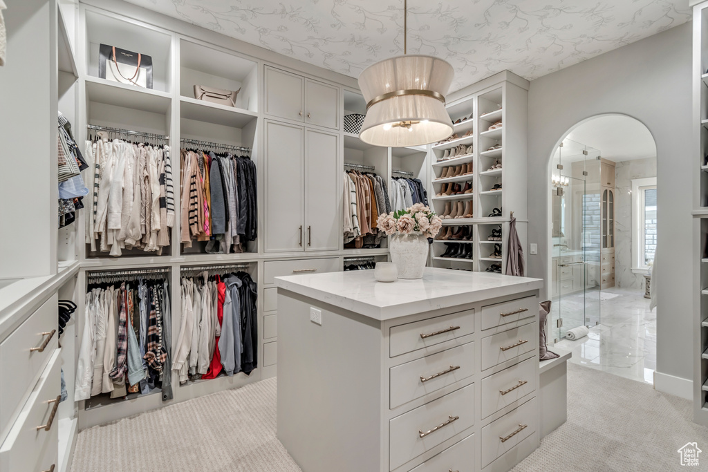 Spacious closet with arched walkways and light carpet