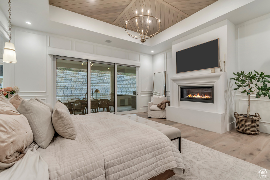 Bedroom featuring wood finished floors, a chandelier, access to exterior, a decorative wall, and wooden ceiling