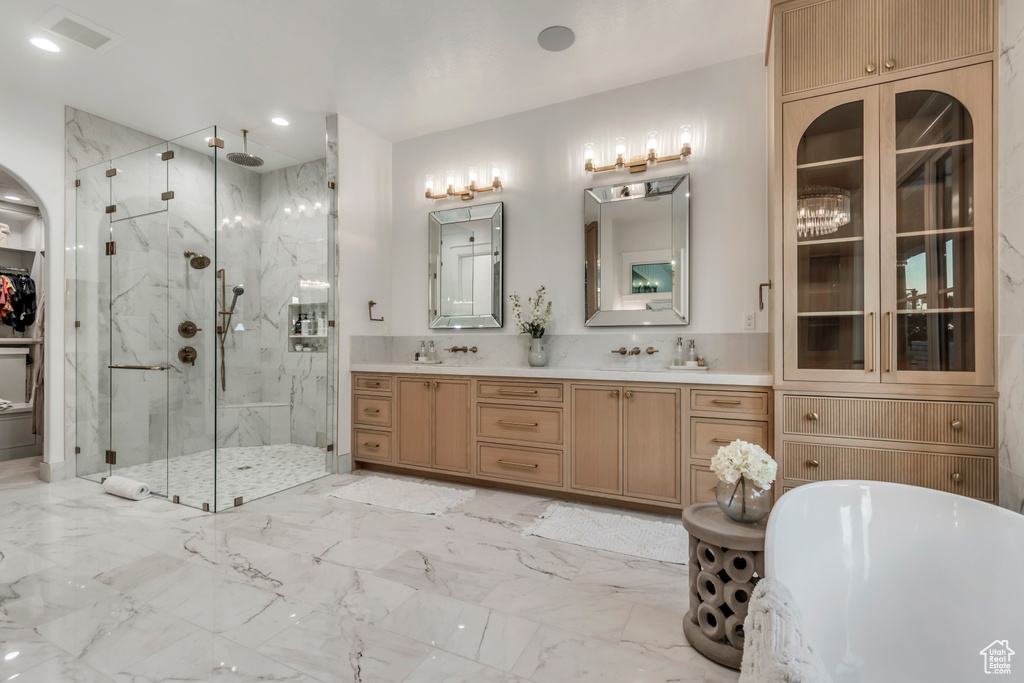Full bath with a marble finish shower, double vanity, a freestanding bath, marble look tiles, and recessed lighting