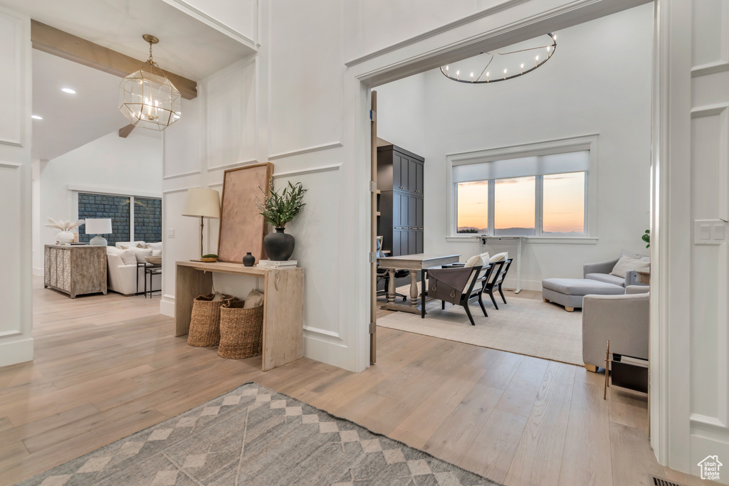 Interior space with high vaulted ceiling, a chandelier, light wood finished floors, and baseboards
