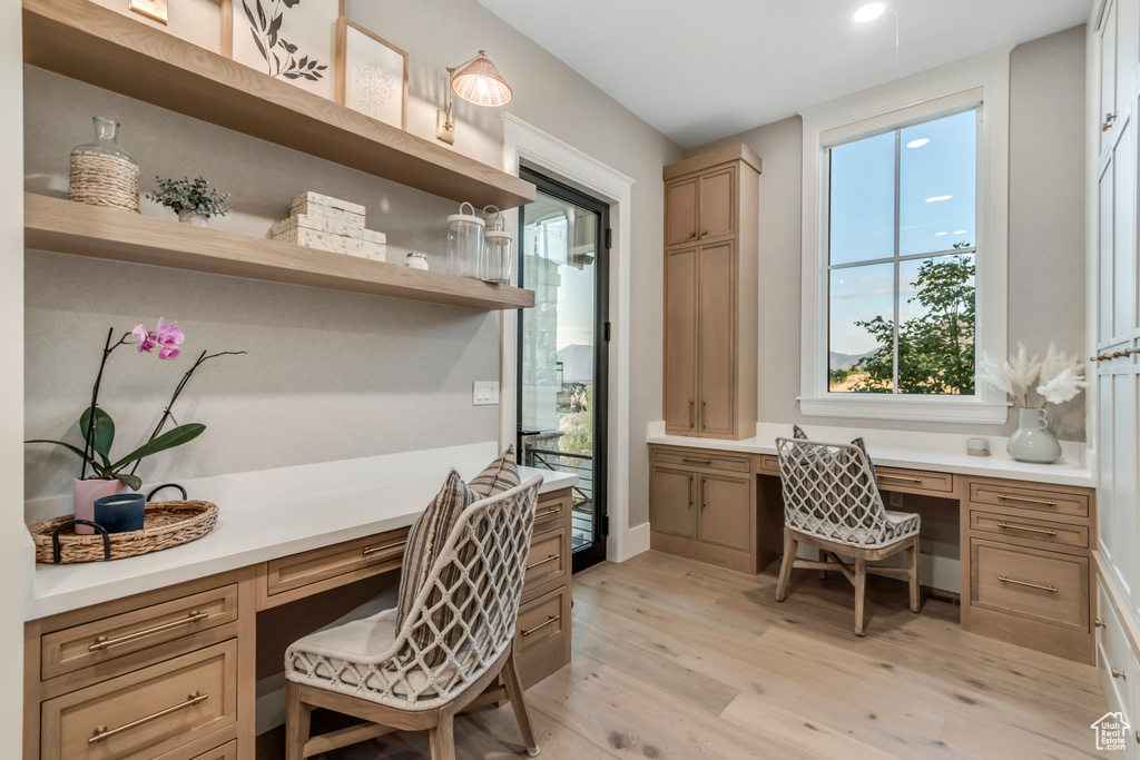 Office space featuring built in desk, light wood-type flooring, plenty of natural light, and recessed lighting