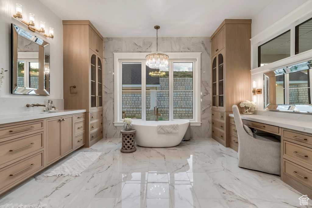 Full bath with a chandelier, a freestanding bath, vanity, and marble tiled floors
