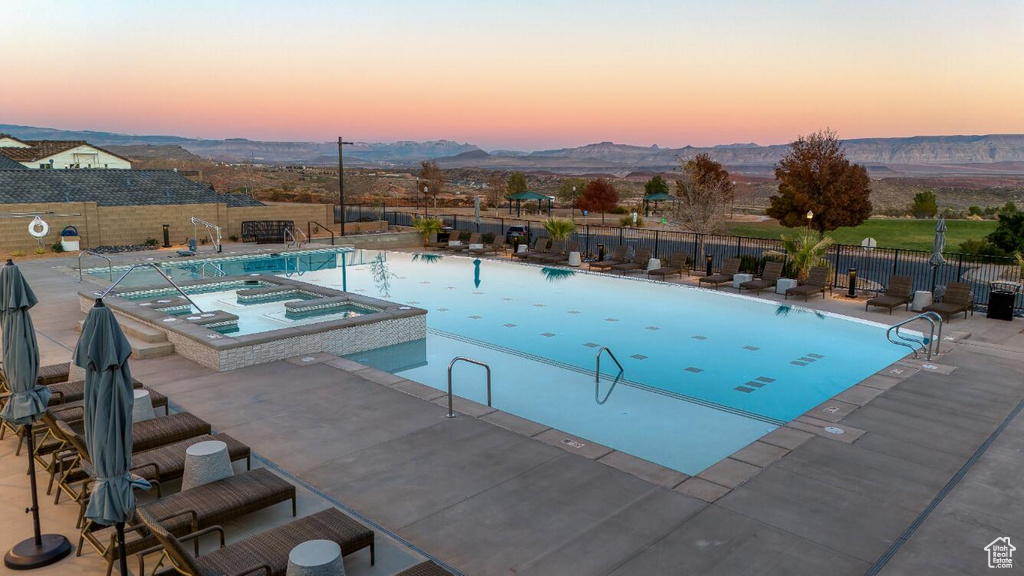 View of swimming pool with a pool with connected hot tub, a patio area, and a mountain view