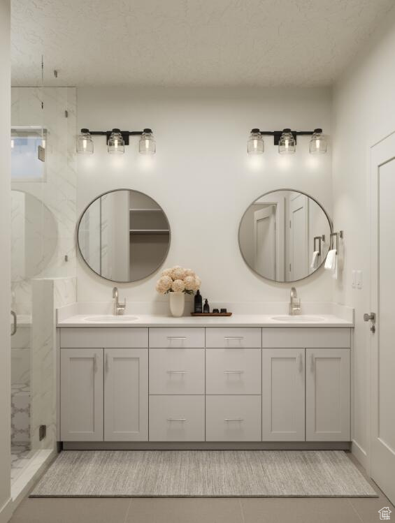 Bathroom with double vanity, a marble finish shower, a textured ceiling, and tile patterned flooring