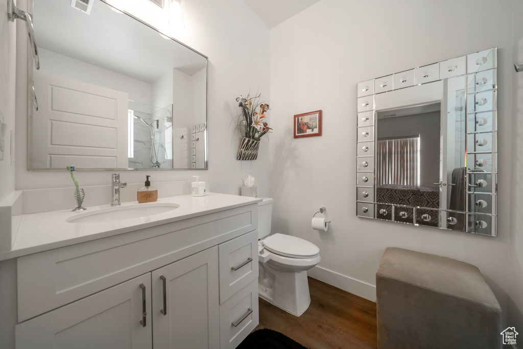 Full bath with wood finished floors, tiled shower, toilet, baseboards, and vanity