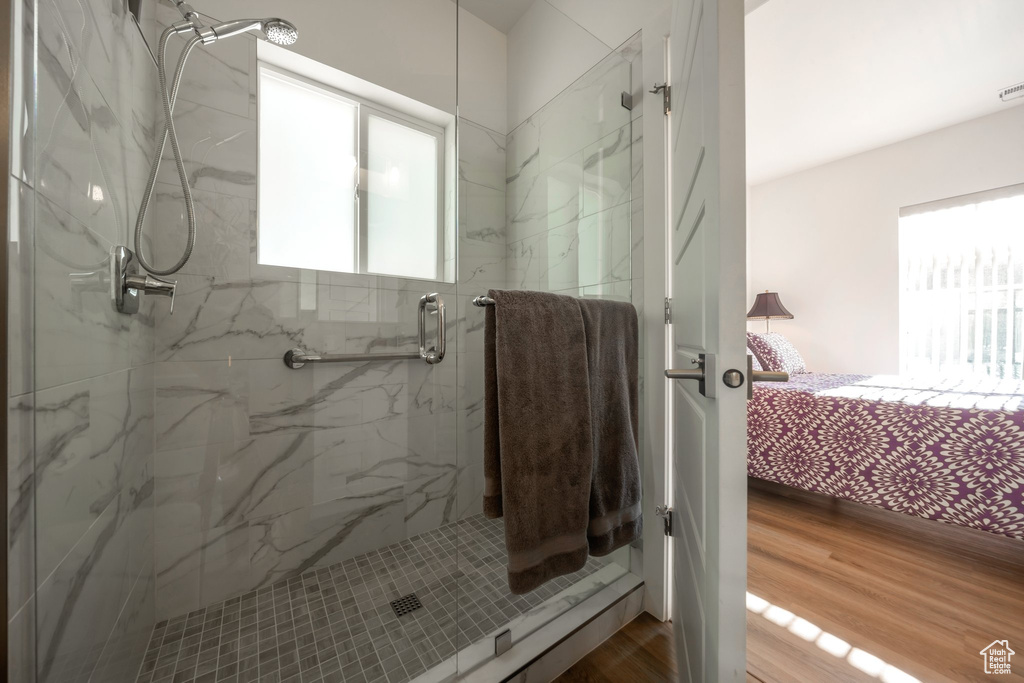 Full bathroom featuring healthy amount of natural light, a marble finish shower, ensuite bathroom, and wood finished floors