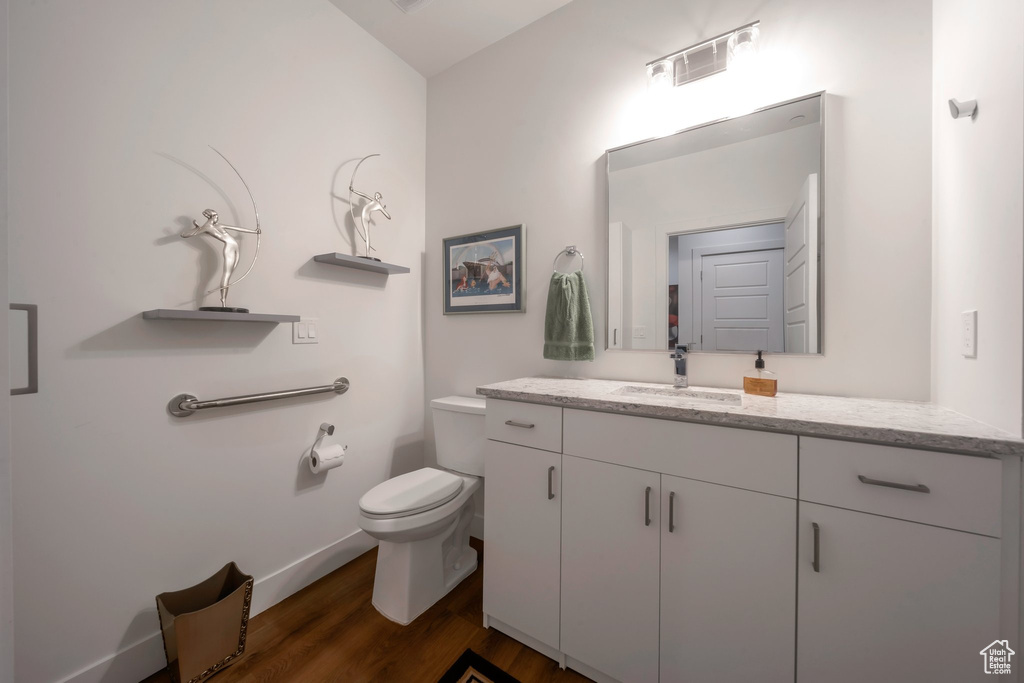 Bathroom with vanity, wood finished floors, toilet, and baseboards