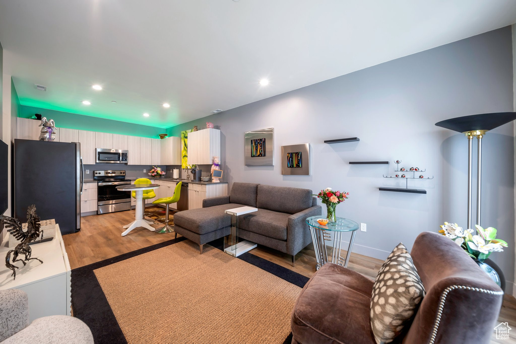 Living room with light wood finished floors, recessed lighting, and baseboards