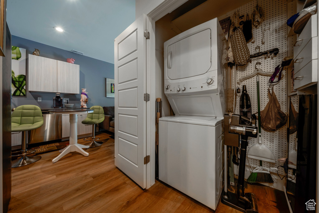 Laundry room with stacked washing machine and dryer, light wood finished floors, an office area, and recessed lighting