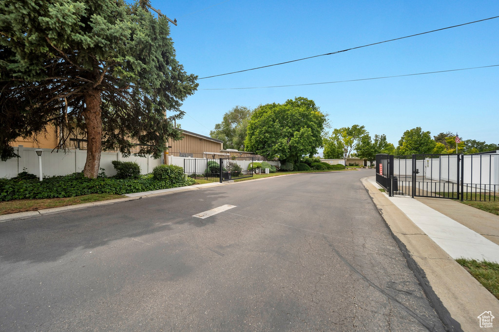 View of asphalt street with curbs, a gate, and sidewalks