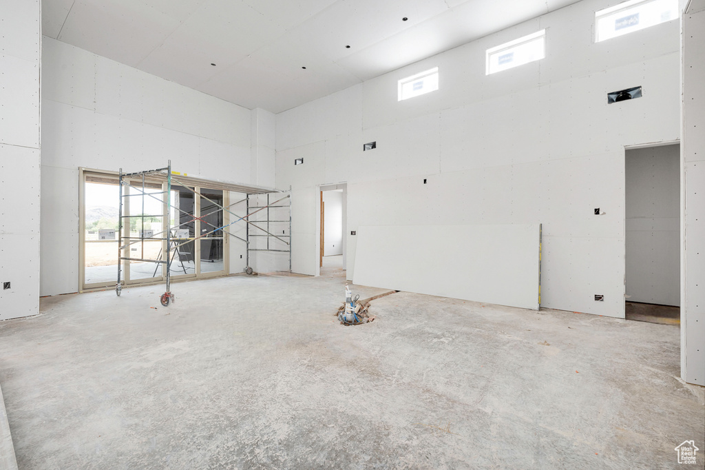 Empty room featuring high vaulted ceiling and concrete floors