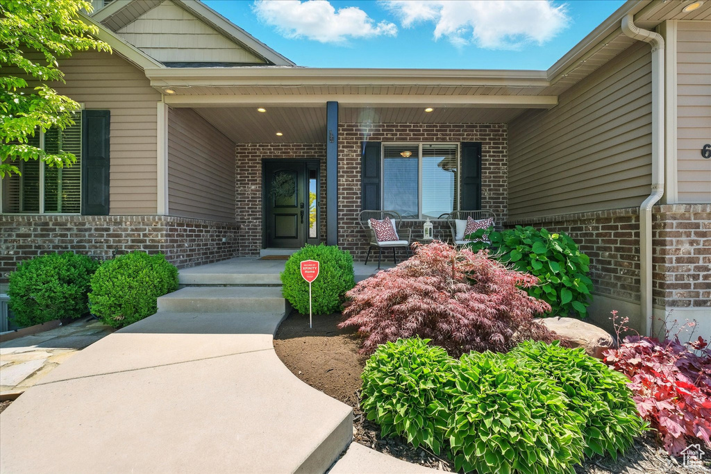 Entrance to property with brick siding and a porch