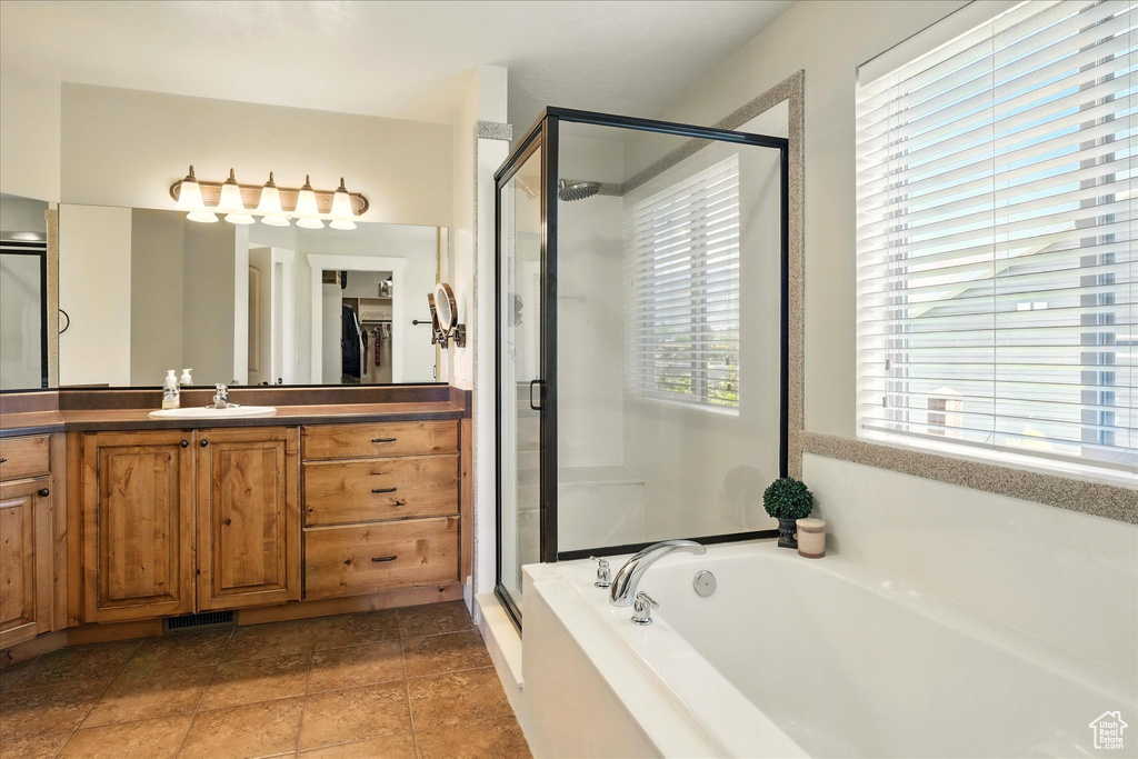 Bathroom featuring a shower stall, a garden tub, healthy amount of natural light, and vanity