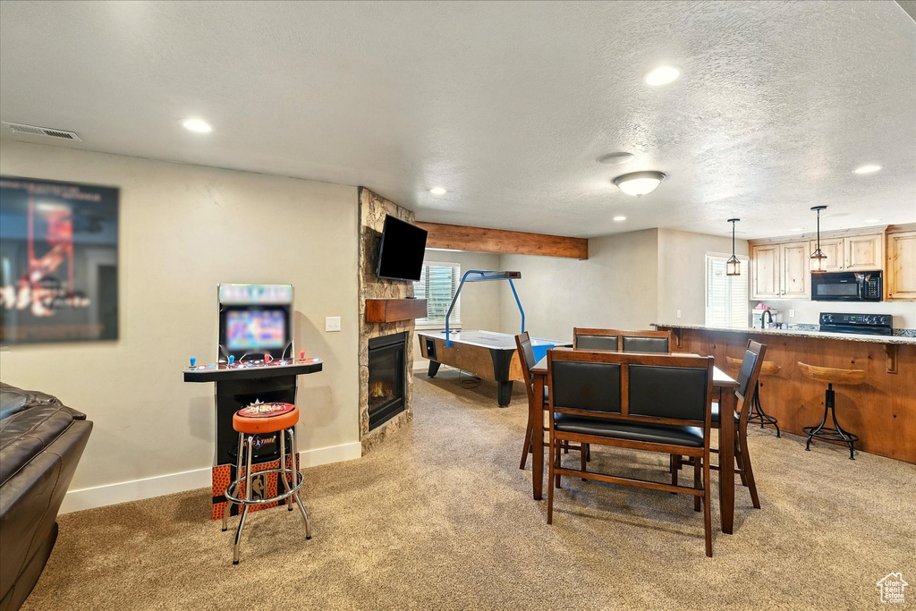 Dining room with light carpet, recessed lighting, a stone fireplace, a textured ceiling, and baseboards