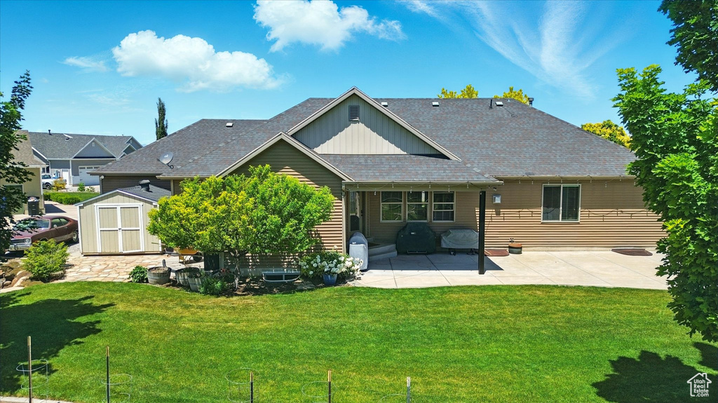 Back of property featuring board and batten siding, a patio area, a yard, and roof with shingles