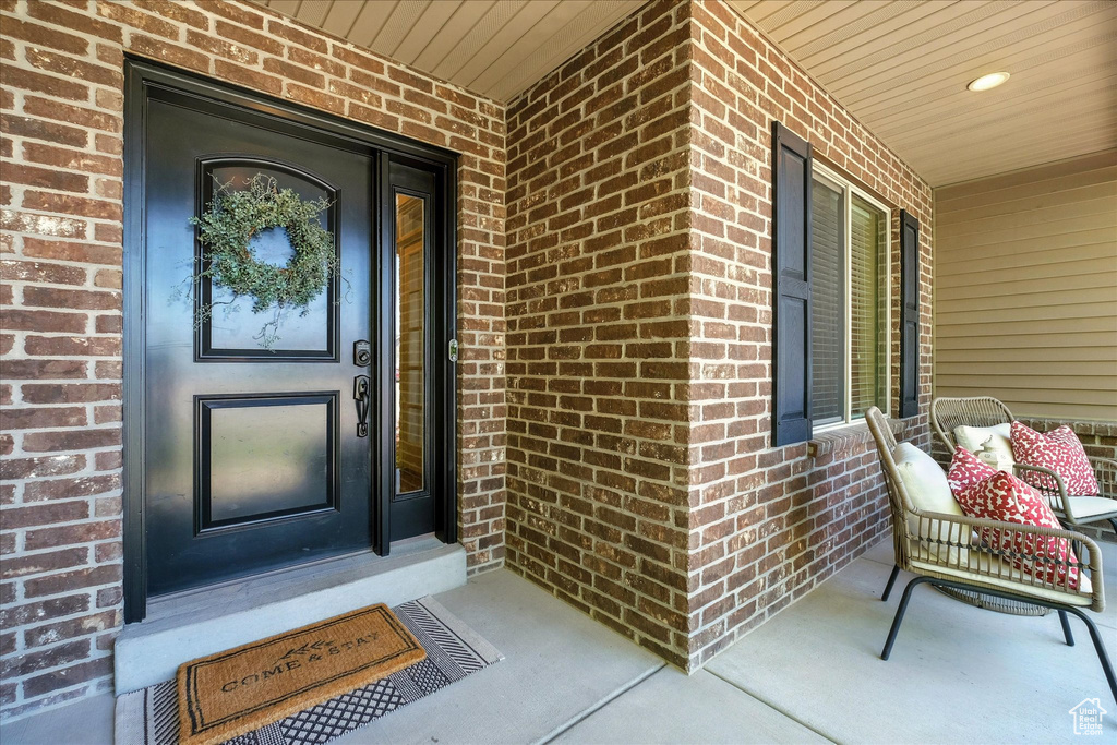 View of exterior entry with brick siding and a porch