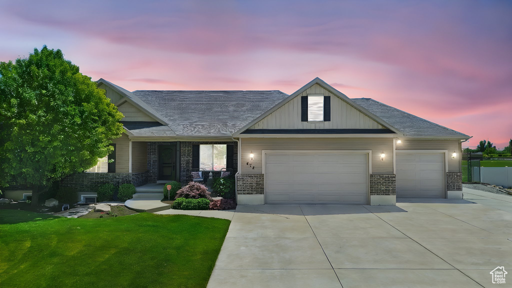 View of front of house featuring an attached garage, driveway, a front yard, and brick siding