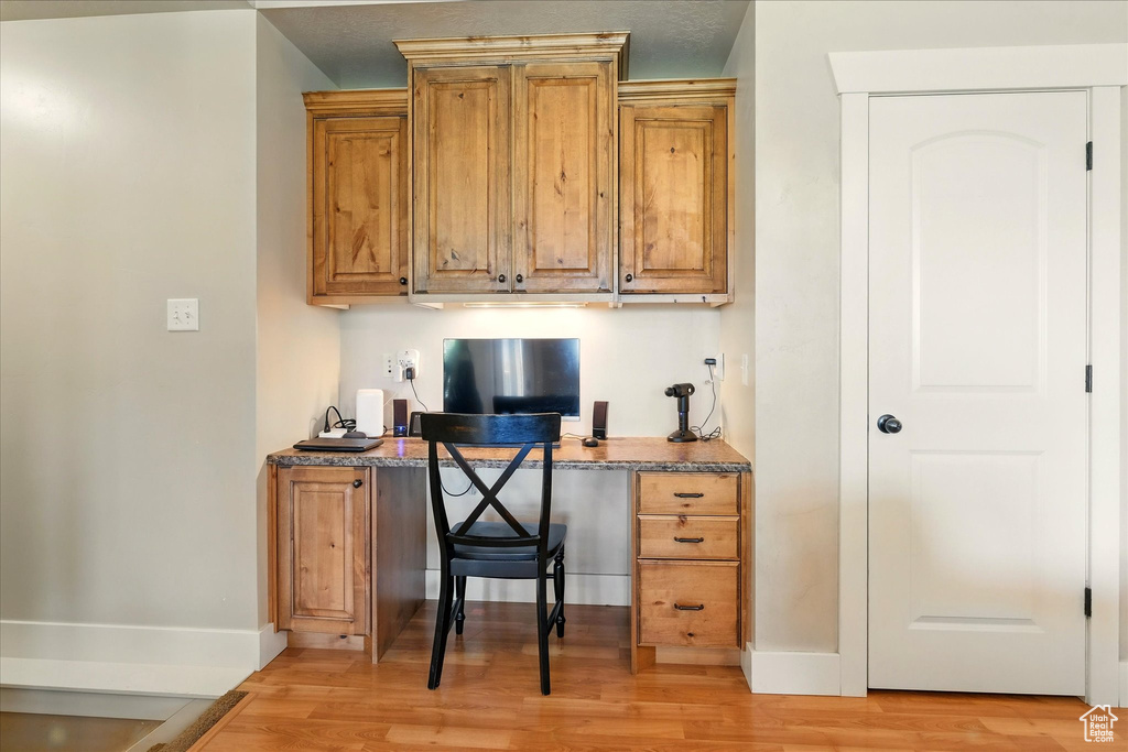 Office with light wood-style flooring, baseboards, and built in study area