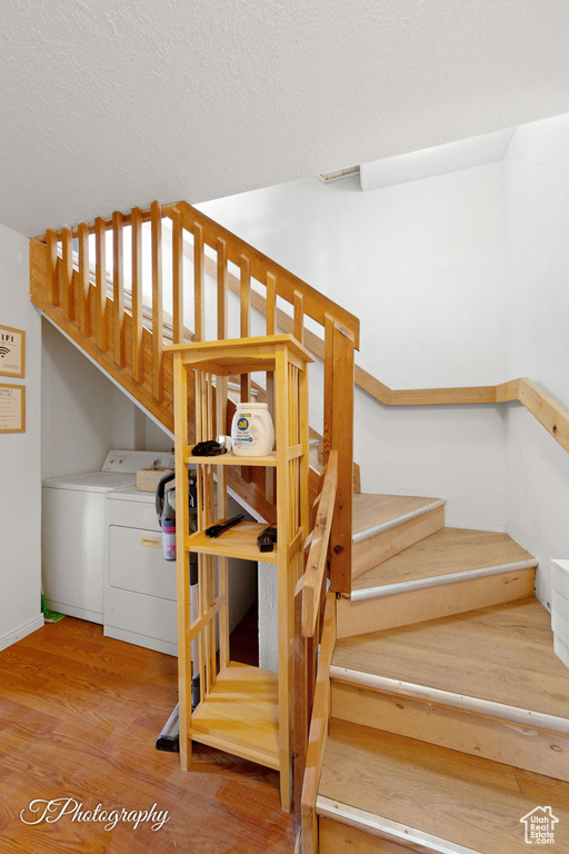 Staircase featuring washer and dryer, wood finished floors, a textured ceiling, and baseboards