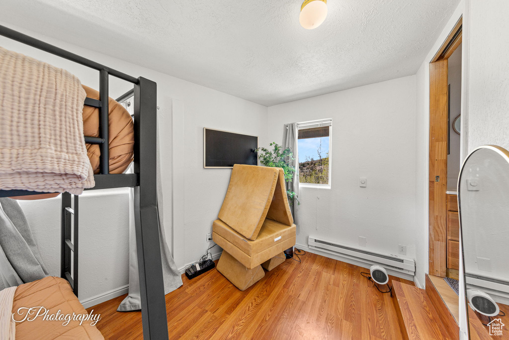 Interior space featuring a baseboard radiator, light wood-style flooring, a textured ceiling, and baseboards