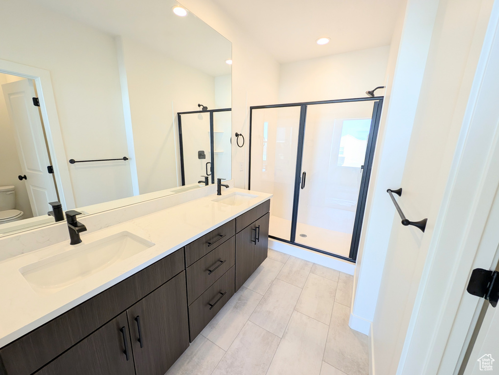 Bathroom with toilet, a shower stall, double vanity, and recessed lighting