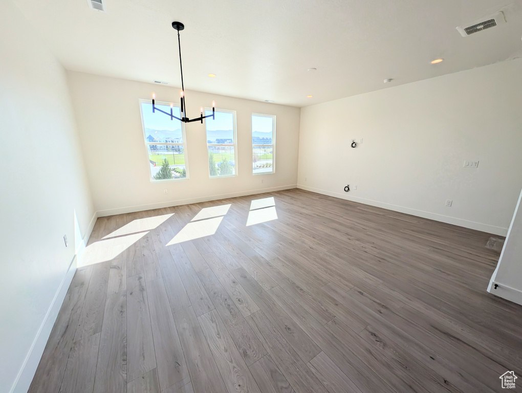 Unfurnished dining area featuring a chandelier, wood finished floors, and baseboards