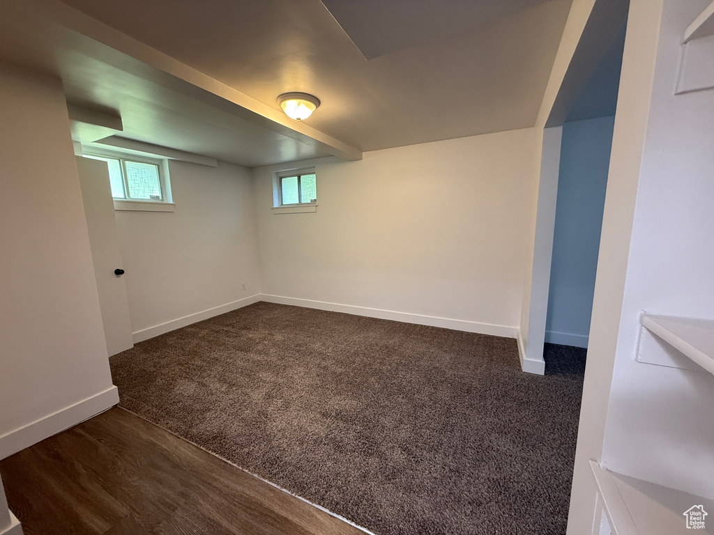 Basement with baseboards and dark colored carpet