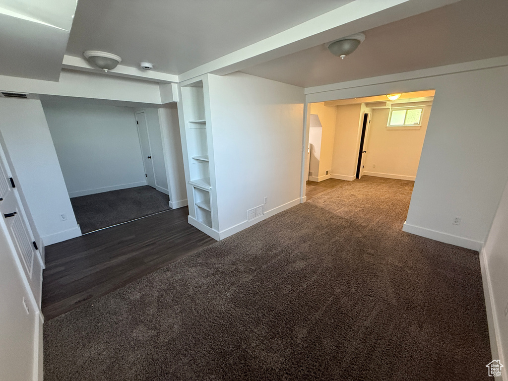 Basement with baseboards, carpet floors, built in shelves, and wood finished floors