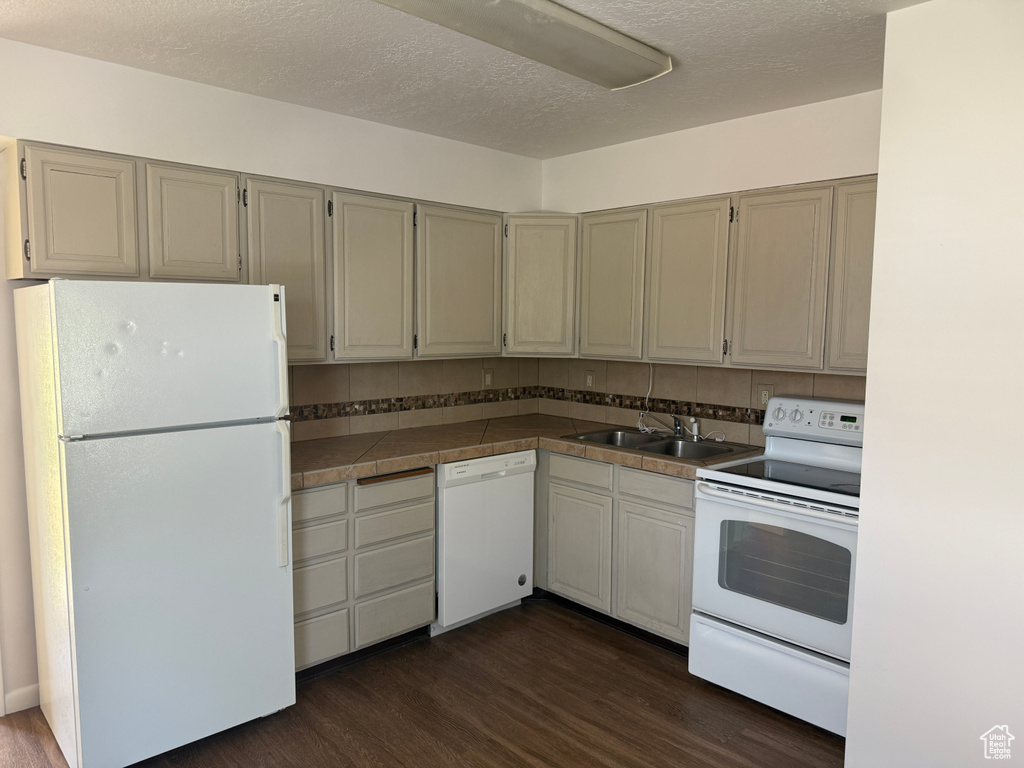 Kitchen featuring white appliances, a sink, dark wood finished floors, and a textured ceiling