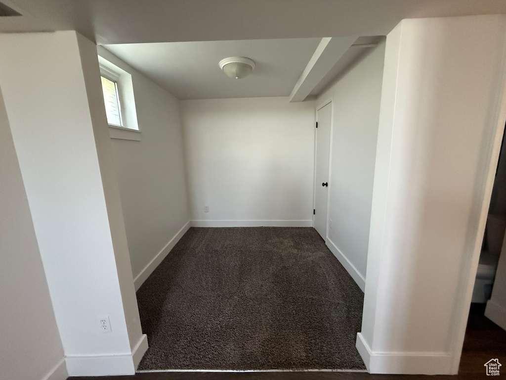 Below grade area with dark carpet and baseboards