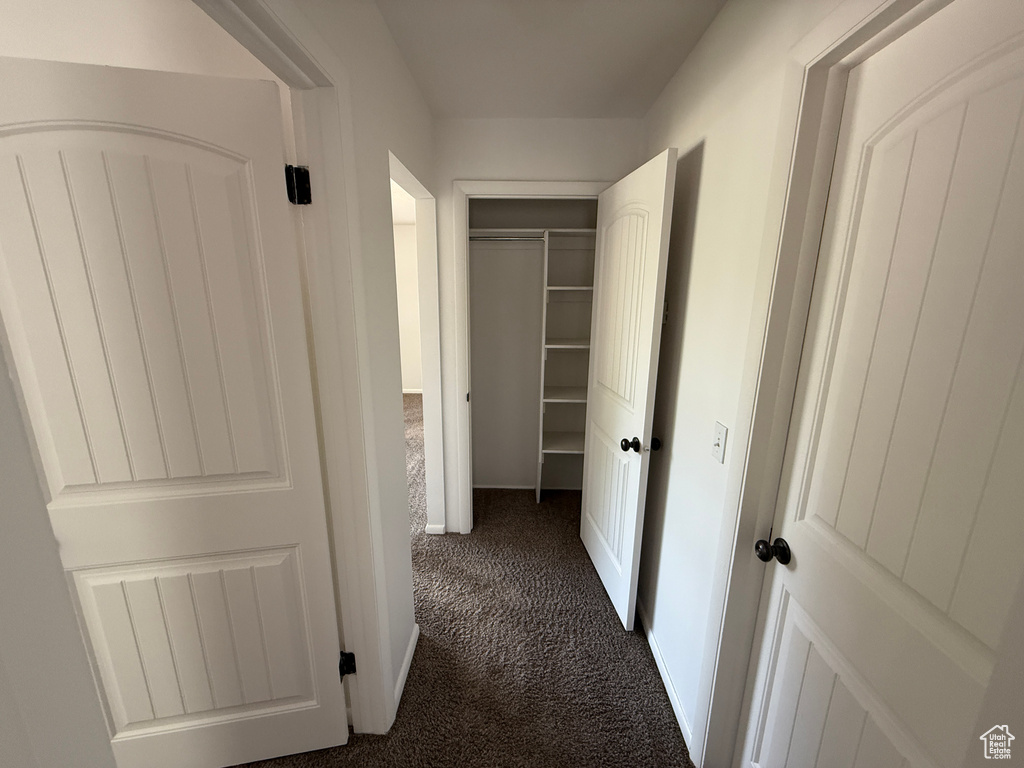 Hall featuring dark colored carpet