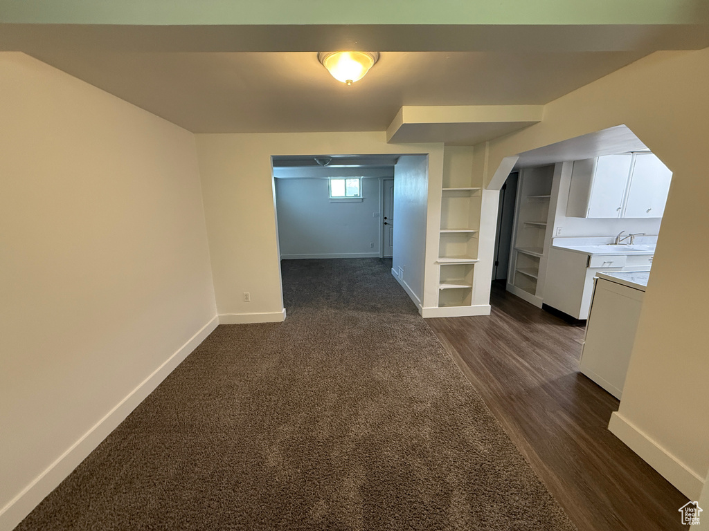 Basement featuring baseboards, dark wood-style floors, built in features, and arched walkways