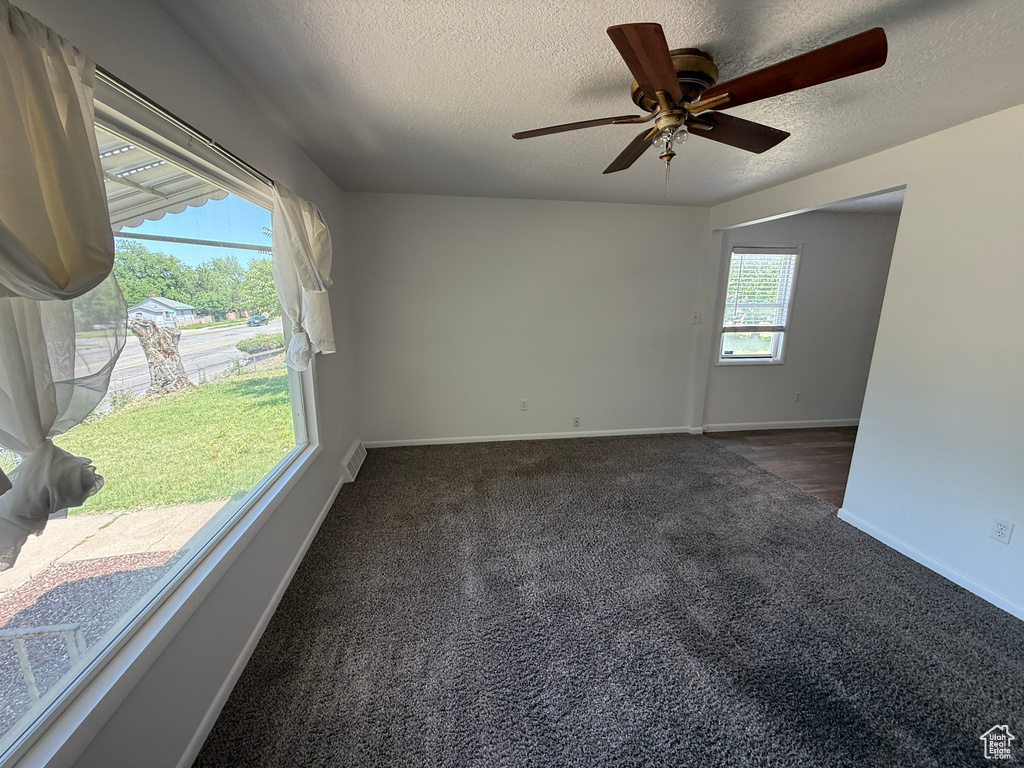 Empty room featuring carpet floors, a textured ceiling, baseboards, and ceiling fan
