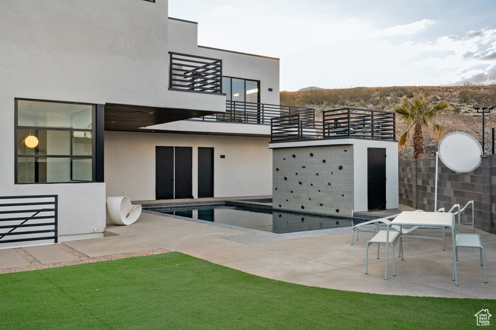 Back of house featuring a balcony, a patio area, and stucco siding