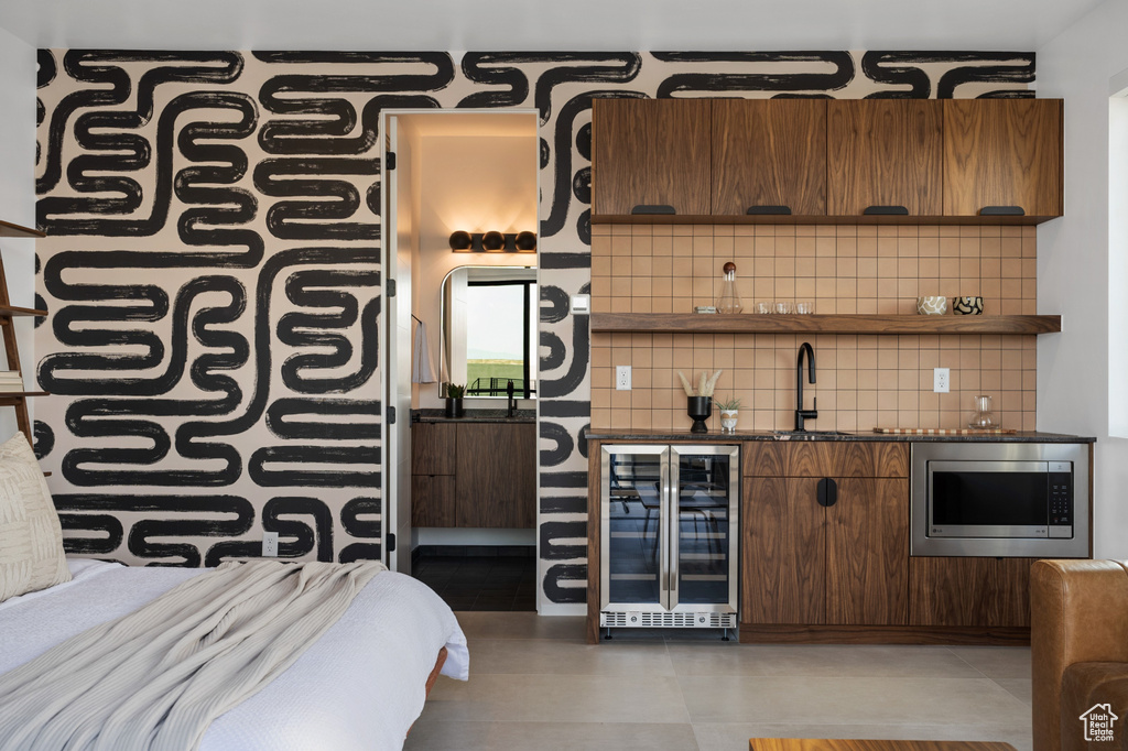Indoor wet bar featuring wine cooler, stainless steel microwave, and decorative backsplash