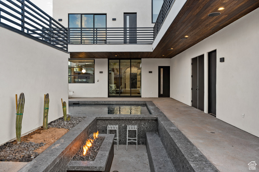 View of patio / terrace with an outdoor fire pit and a balcony