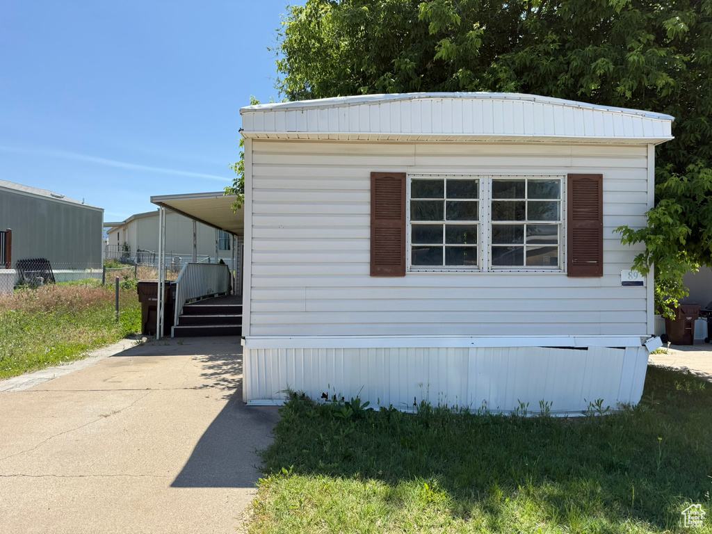 View of property exterior with concrete driveway and a carport