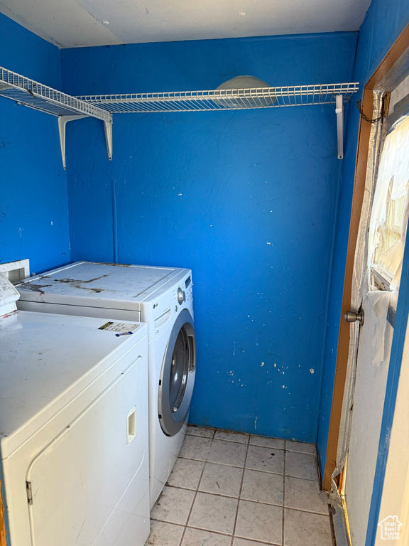 Laundry area featuring washing machine and clothes dryer and light tile patterned flooring