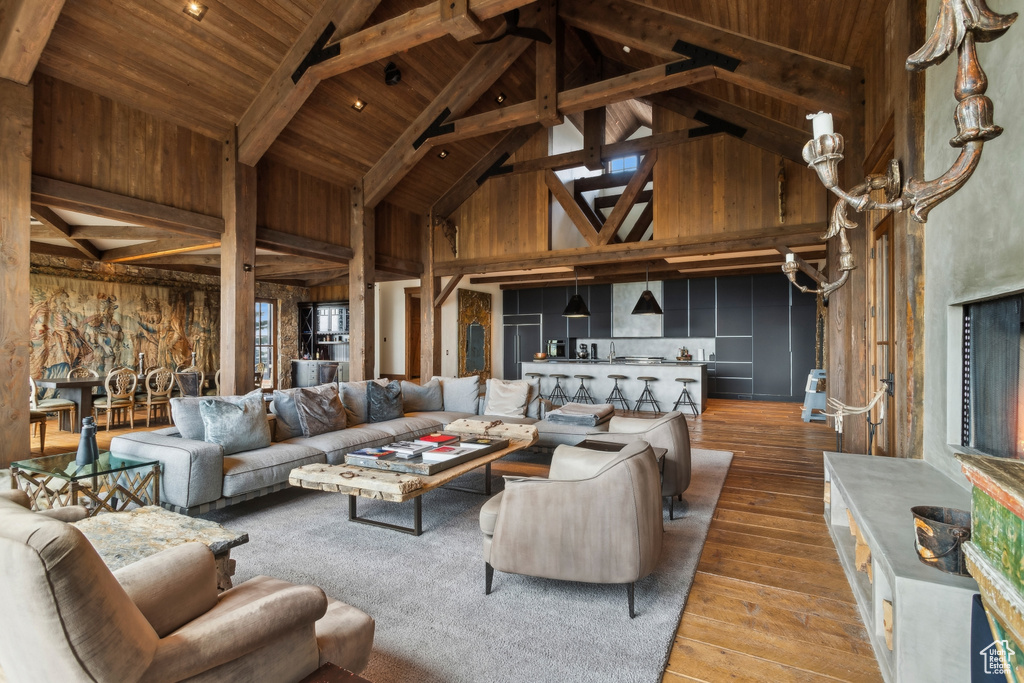 Living room featuring hardwood / wood-style floors, high vaulted ceiling, wooden ceiling with exposed beams, and wood walls