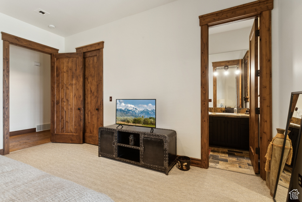 Bedroom featuring carpet, a sink, ensuite bath, and baseboards