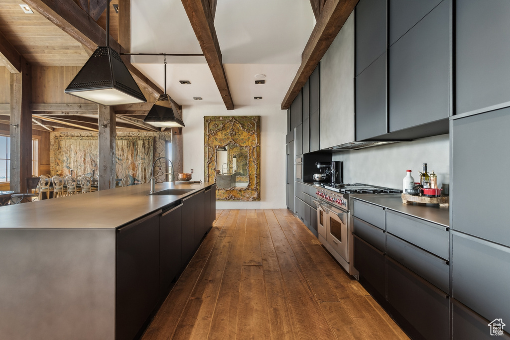 Kitchen featuring double oven range, a sink, beamed ceiling, modern cabinets, and dark wood-style flooring