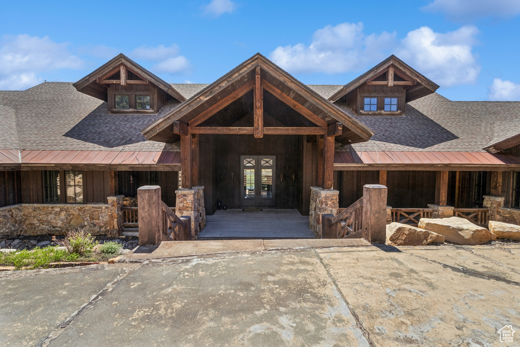 View of front of property featuring a shingled roof, french doors, stone siding, and a standing seam roof