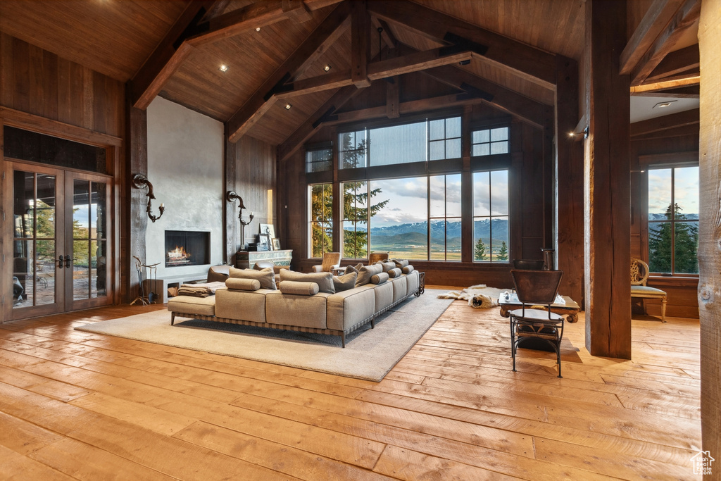 Living room with high vaulted ceiling, hardwood / wood-style flooring, french doors, wood ceiling with exposed beams, and a fireplace