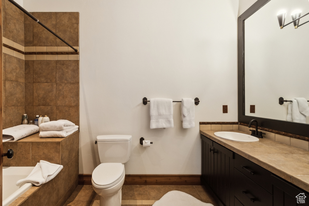 Bathroom with toilet, tiled tub, vanity, tile patterned floors, and tiled shower