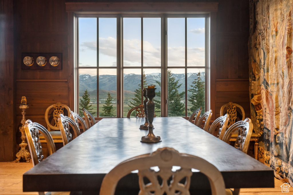 Dining area with a mountain view, wood walls, healthy amount of natural light, and wood finished floors