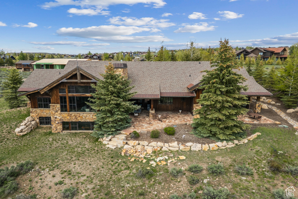 Rear view of property featuring stone siding and roof with shingles